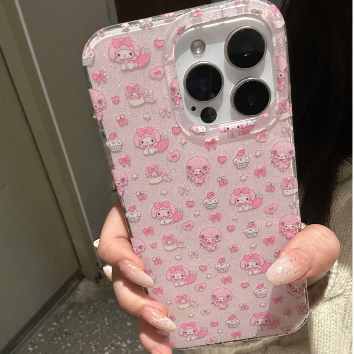 A person holding a pink iPhone case featuring the character My Melody with a lanyard.