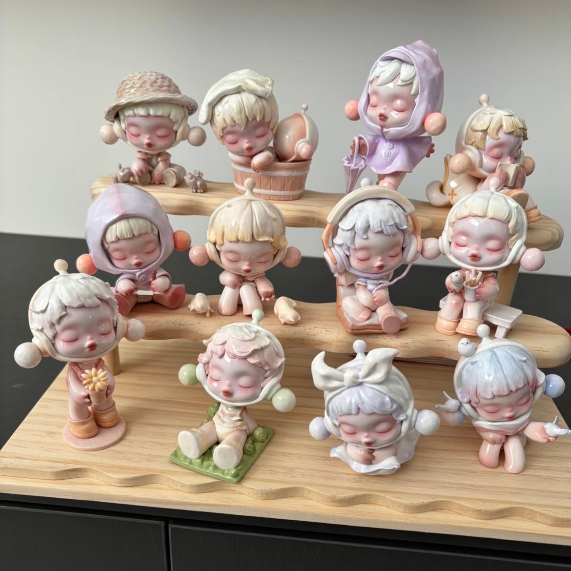 Collection of Pop Mart Skullpanda small figurines on a wooden stand against a neutral background