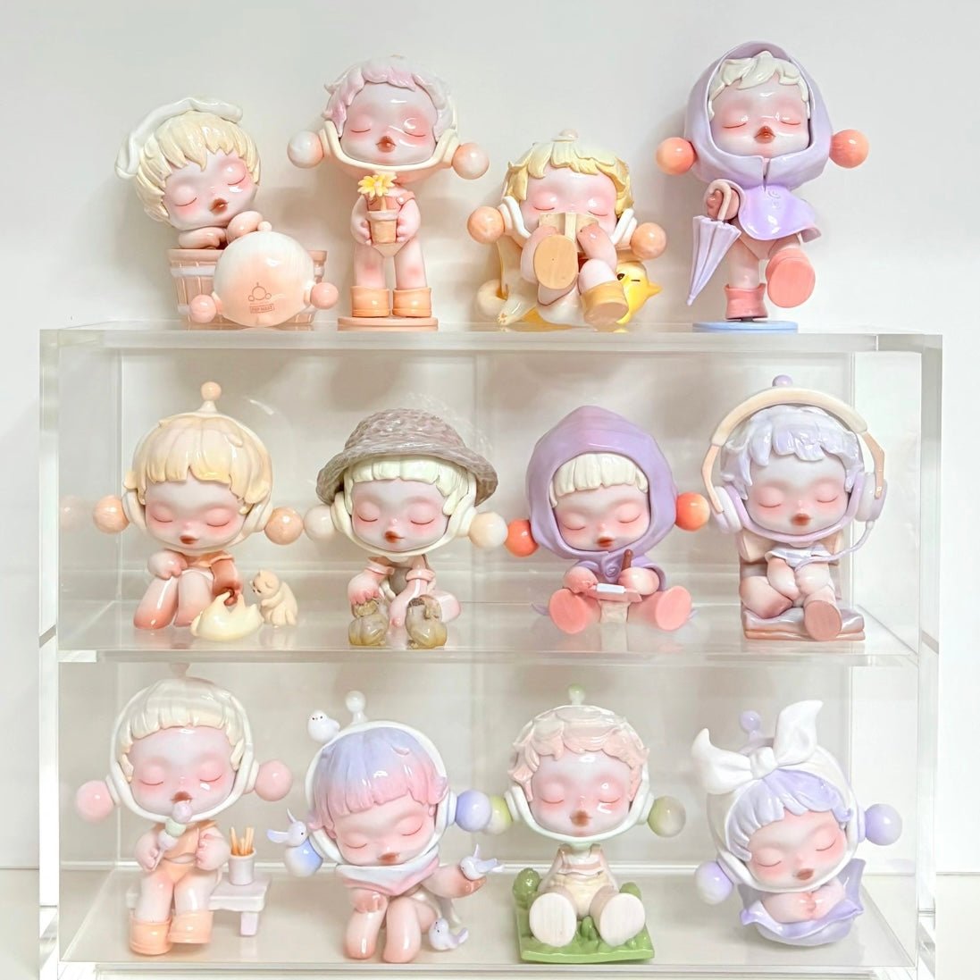 Collection of Pop Mart Skullpanda small figurines with pastel colors on a white shelf.