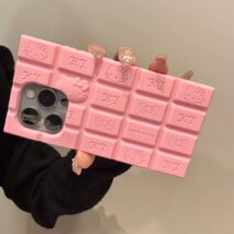 A person holding a chocolate-colored silicone iPhone case featuring Rilakkuma and Hello Kitty characters.